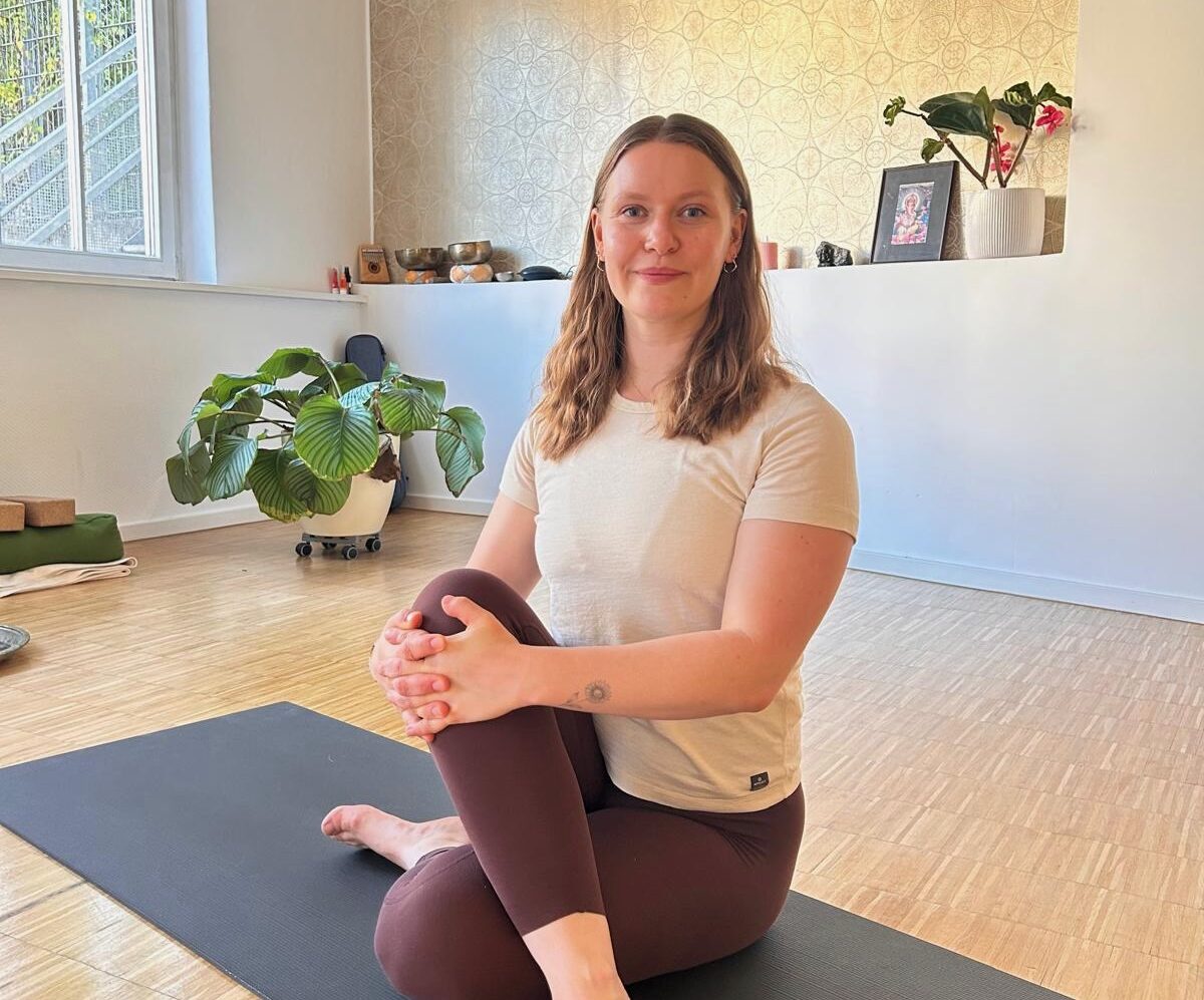 Yogalehrerin Hanna Heuer sitzt auf einer grauen Yogamatte im Yogastudio Fuß über Kopf.