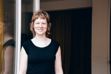 Yogalehrerin Christiane Havenith schaut zur Terrassentür des Yogastudios Fuß über Kopf in den Hinterhof im Stuttgarter Westen hinaus und lächelt freundlich