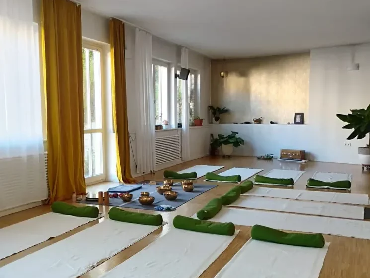 Ein heller freundlicher Yogaraum, in dem Yogamatten und Kissen sowie Klangschalen ausliegen für ein Sound Bath und Klangmassage im Yogastudio Fuß über Kopf